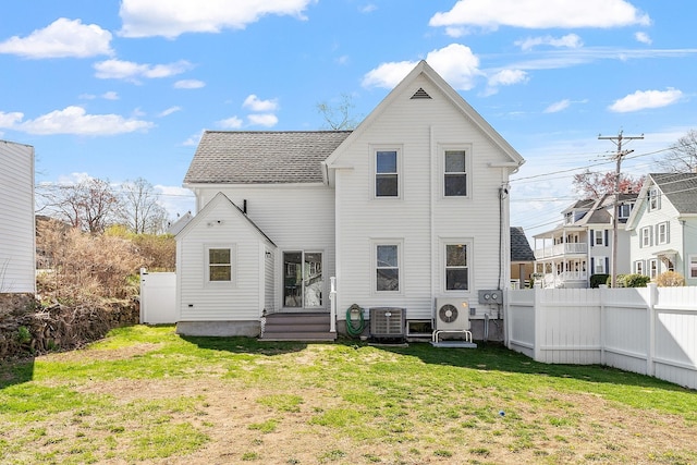 rear view of property with a shingled roof, central AC unit, a yard, ac unit, and fence