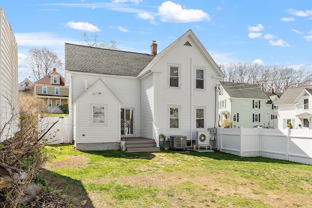 rear view of house featuring a lawn, a chimney, and fence