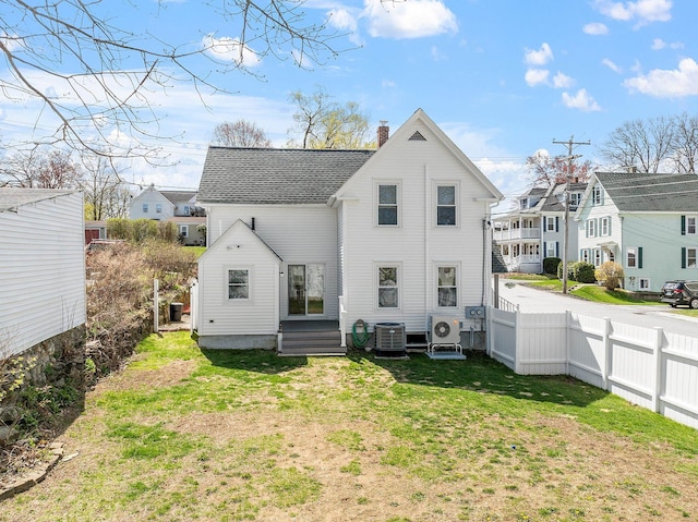 back of property featuring a chimney, ac unit, central air condition unit, fence, and a yard