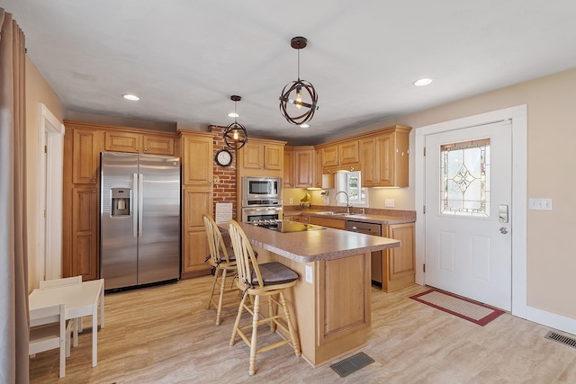 kitchen with visible vents, stainless steel appliances, light wood-style flooring, and a sink