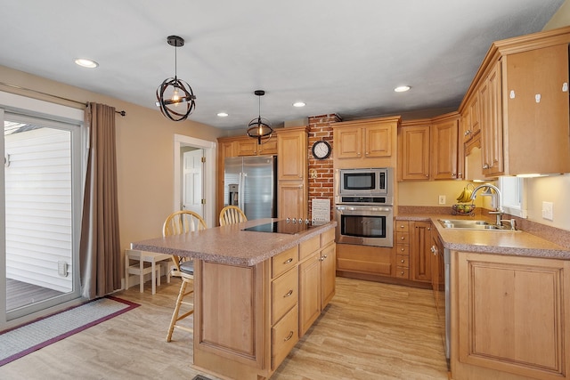 kitchen with a breakfast bar area, a sink, stainless steel appliances, a center island, and light wood-type flooring