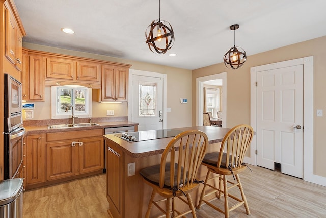 kitchen featuring stainless steel appliances, a kitchen island, light wood-style flooring, and a sink