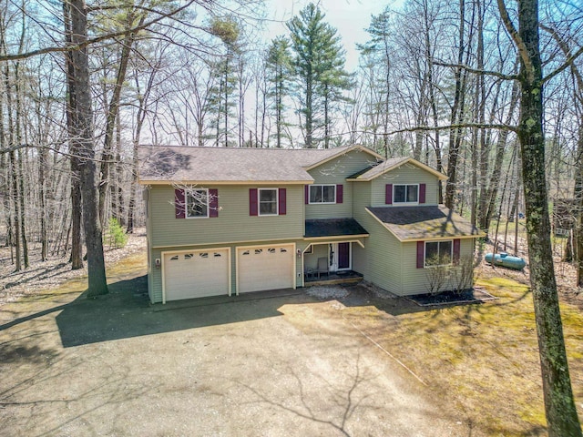 view of front of house featuring dirt driveway, a shingled roof, and a garage