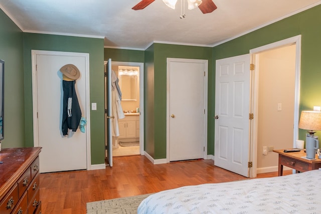bedroom featuring crown molding, ensuite bath, wood finished floors, and baseboards