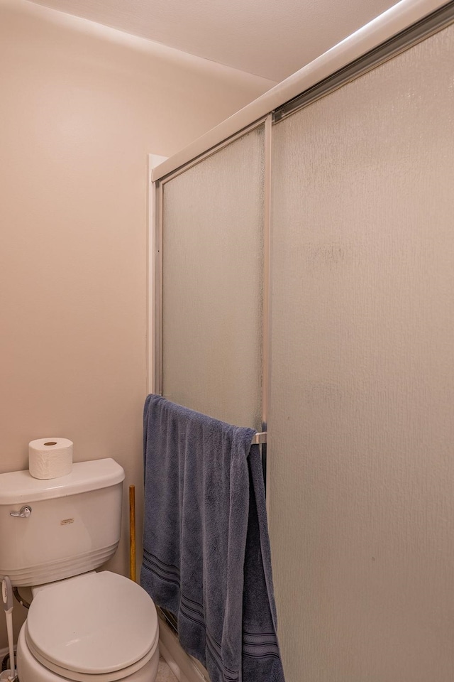 full bathroom featuring toilet and a stall shower