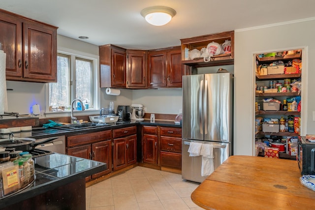 kitchen with freestanding refrigerator, open shelves, dark countertops, a sink, and light tile patterned flooring