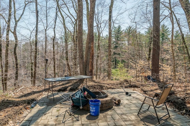 view of patio / terrace with a fire pit and a forest view