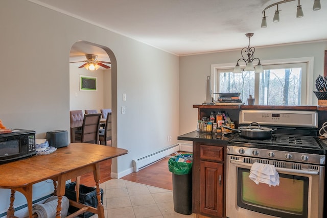 kitchen with a baseboard heating unit, stainless steel range with gas cooktop, light tile patterned floors, black microwave, and dark countertops