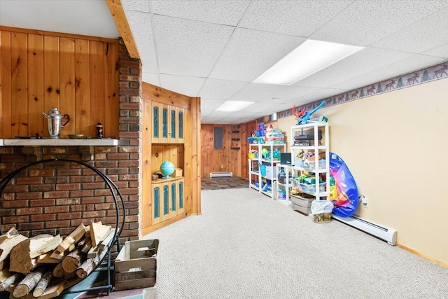 game room featuring a drop ceiling, a baseboard radiator, baseboard heating, carpet flooring, and wooden walls
