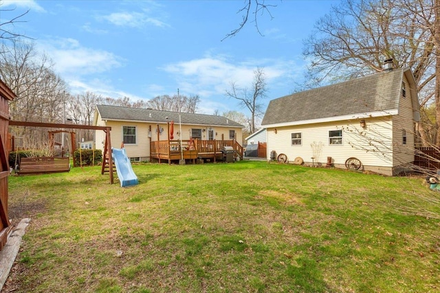 rear view of property featuring fence, a chimney, a yard, and a wooden deck