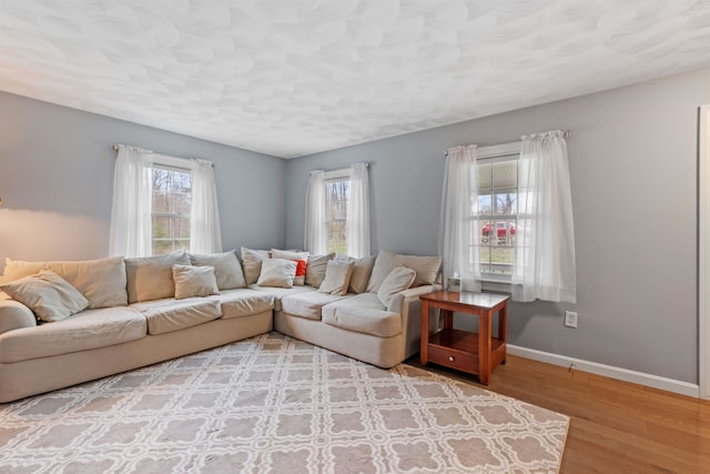 living area featuring a textured ceiling, wood finished floors, and baseboards
