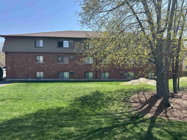 rear view of property with a lawn and brick siding