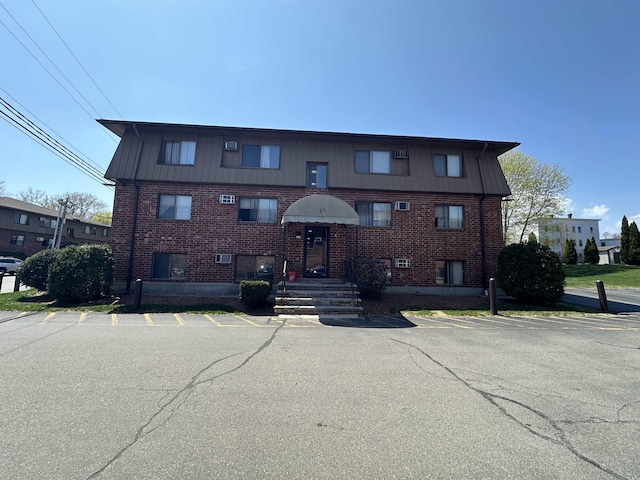 view of front facade with brick siding and uncovered parking