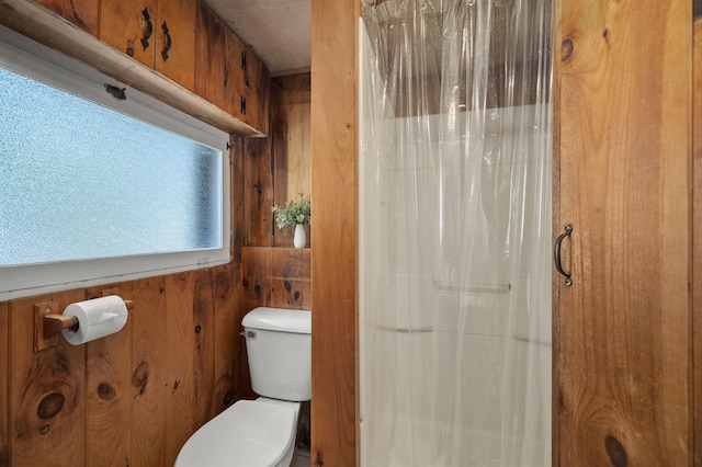 full bathroom featuring wooden walls, toilet, and a shower with shower curtain