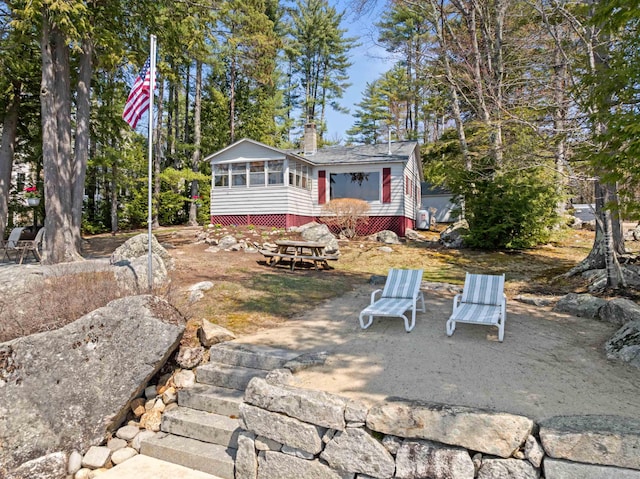 rear view of house with a sunroom and a chimney