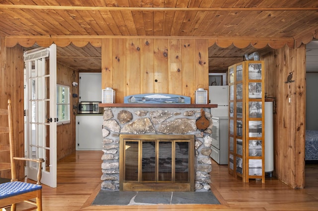 living room with wooden walls, a stone fireplace, hardwood / wood-style flooring, and wood ceiling