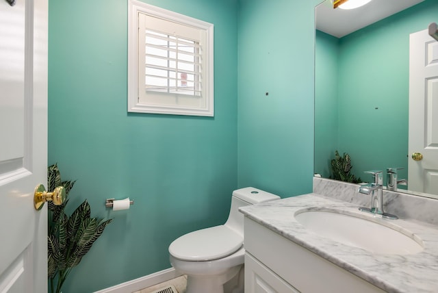 half bathroom with baseboards, toilet, and vanity