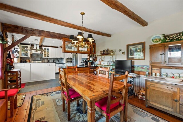 dining room featuring light wood-type flooring, beamed ceiling, and an inviting chandelier