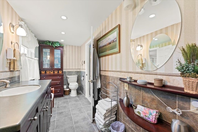 full bathroom featuring recessed lighting, tile walls, tile patterned floors, wainscoting, and wallpapered walls