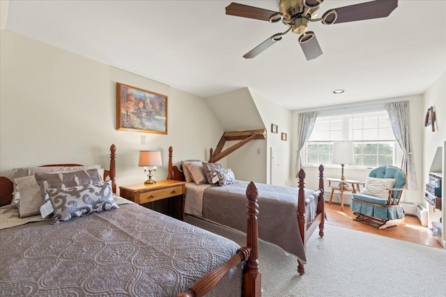 carpeted bedroom with ceiling fan, baseboard heating, and wood finished floors