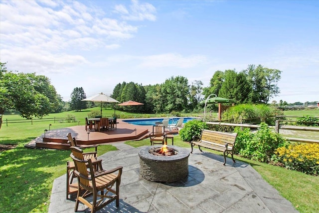 view of patio / terrace with a wooden deck, an outdoor pool, a fire pit, and fence