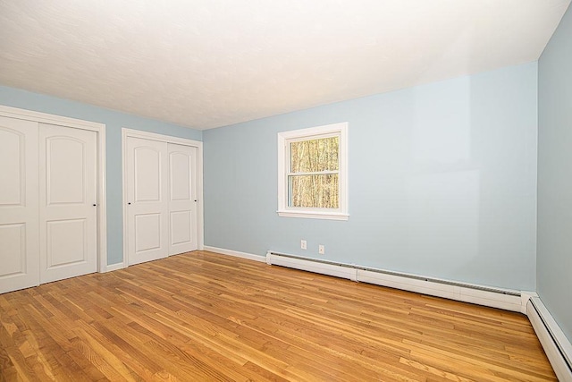 24 Hampton Falls Rd, Exeter, NH 03833 - unfurnished bedroom featuring a baseboard heating unit, multiple closets, wood finished floors, and baseboards