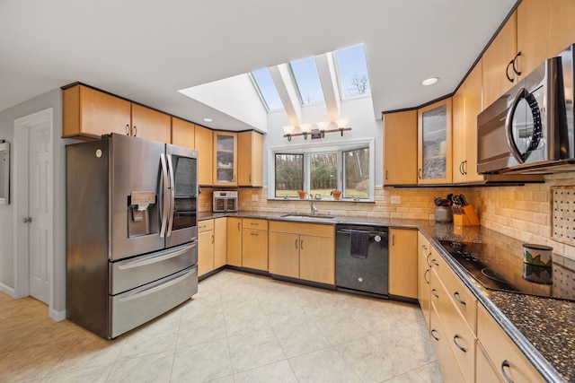 kitchen with recessed lighting, a sink, tasteful backsplash, black appliances, and a skylight