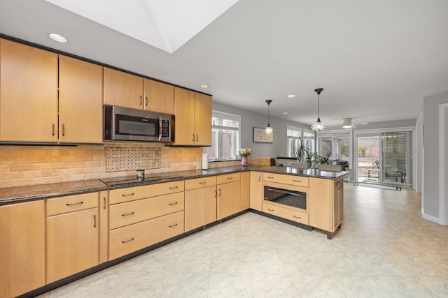 kitchen with stainless steel microwave, light brown cabinetry, a warming drawer, backsplash, and a peninsula