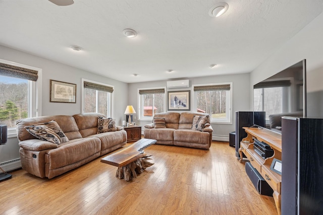 living room with baseboard heating, a wall unit AC, and light wood-style floors