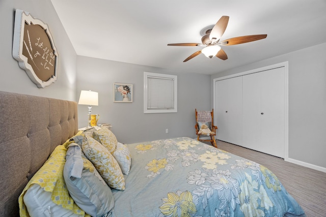 bedroom featuring baseboards, wood finished floors, ceiling fan, and a closet