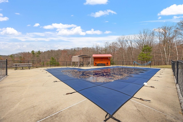 view of swimming pool featuring a wooded view, a fenced in pool, and fence