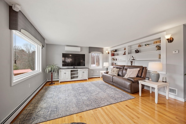 living area with light wood-style floors, a wall mounted AC, a baseboard heating unit, and baseboards