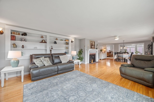 living area with a fireplace with flush hearth, wood finished floors, and baseboards