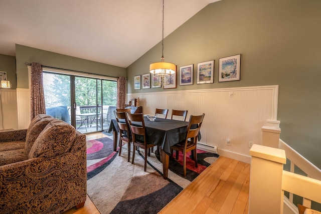 dining space featuring wood finished floors, a wainscoted wall, high vaulted ceiling, a baseboard heating unit, and a notable chandelier
