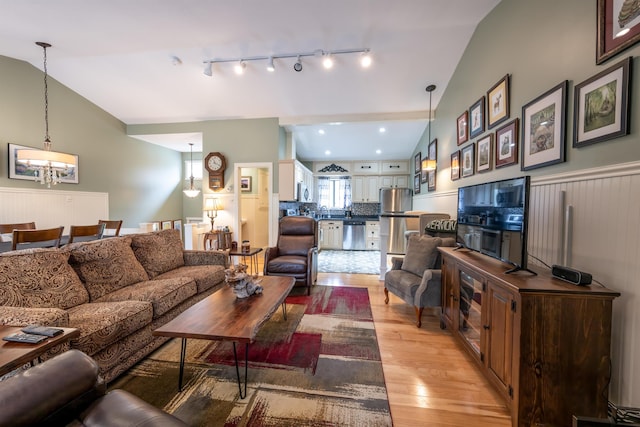 living area featuring a notable chandelier, lofted ceiling, and light wood-style floors