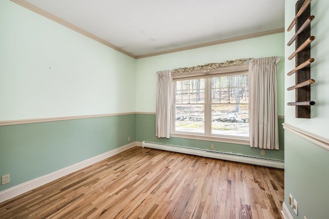unfurnished room featuring a baseboard radiator, wood finished floors, ornamental molding, and baseboards