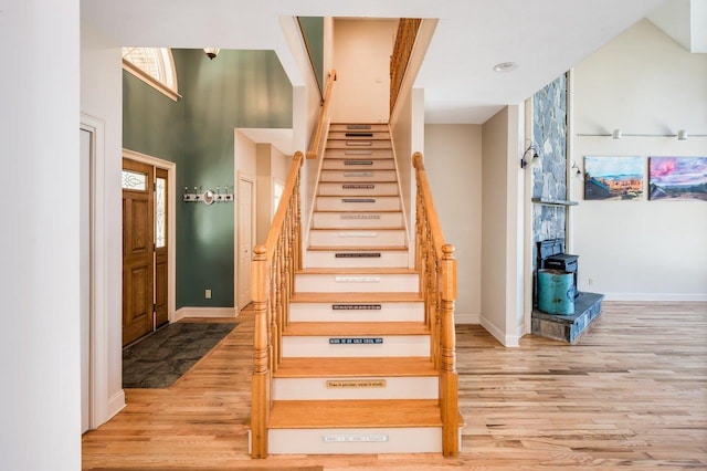 stairway with baseboards, a wood stove, and wood finished floors