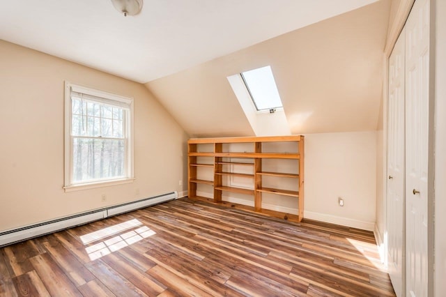 bonus room with baseboards, wood finished floors, a baseboard heating unit, and vaulted ceiling with skylight