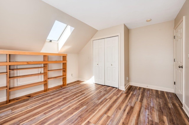 additional living space with wood finished floors, baseboards, and vaulted ceiling with skylight