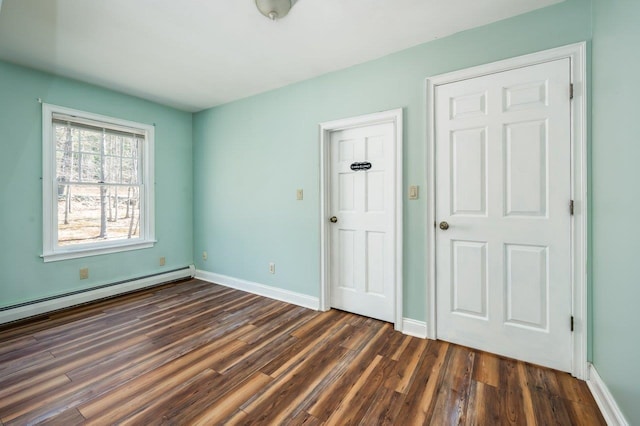 unfurnished bedroom featuring baseboard heating, baseboards, and dark wood-style flooring