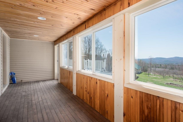 unfurnished sunroom featuring wooden ceiling, a mountain view, wood walls, and wood-type flooring