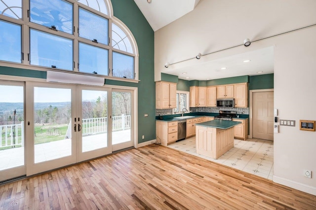 kitchen with a sink, appliances with stainless steel finishes, light brown cabinetry, light wood-type flooring, and french doors