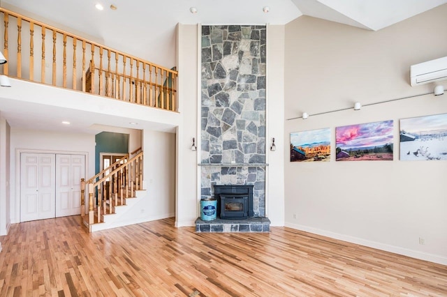 unfurnished living room featuring wood finished floors, baseboards, high vaulted ceiling, and stairs