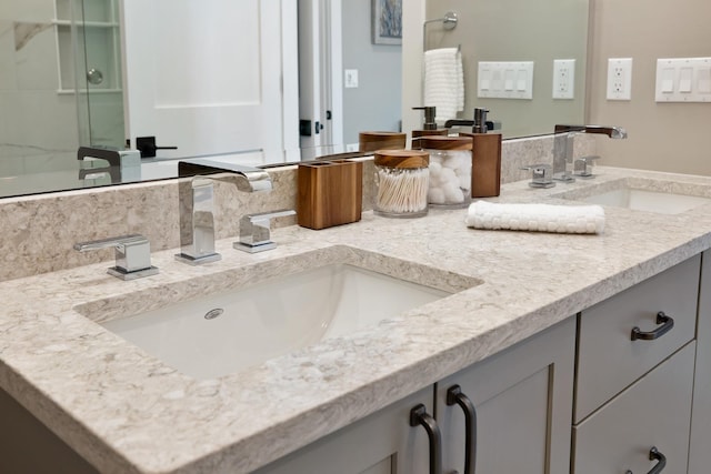 bathroom featuring a shower with shower door, double vanity, and a sink
