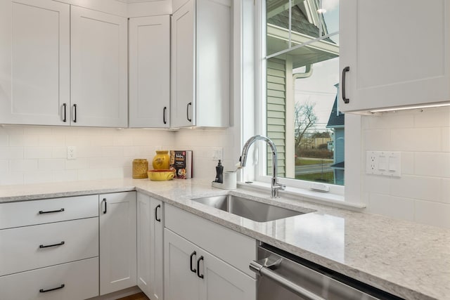 kitchen with dishwasher, a sink, white cabinets, and decorative backsplash