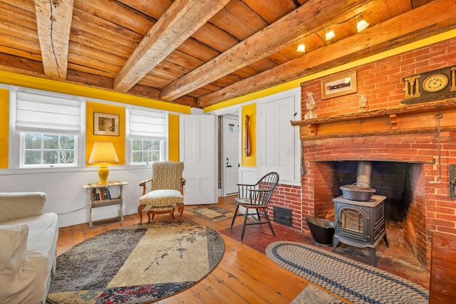 living room with beam ceiling, a wood stove, wood-type flooring, and wood ceiling