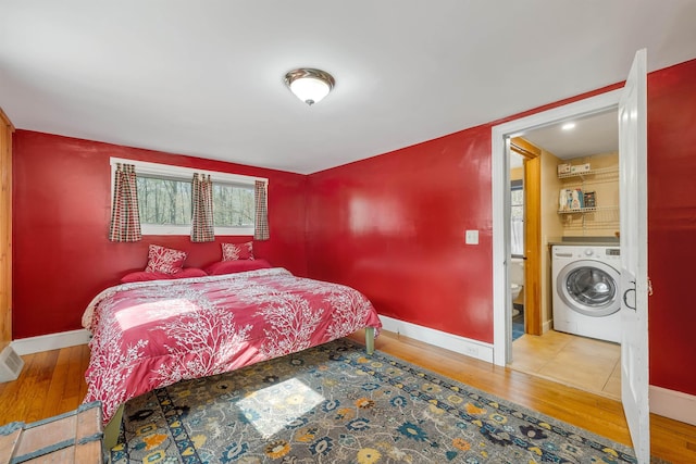 bedroom with wood finished floors, washer / dryer, and baseboards