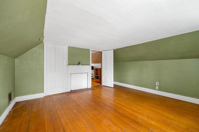 bonus room with wood-type flooring, lofted ceiling, and baseboards