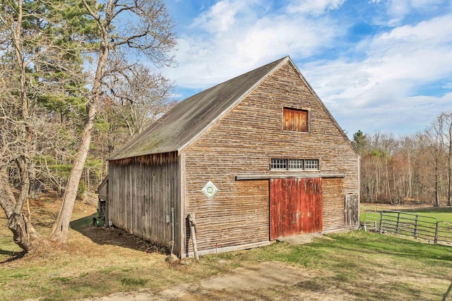 view of barn with fence and a lawn