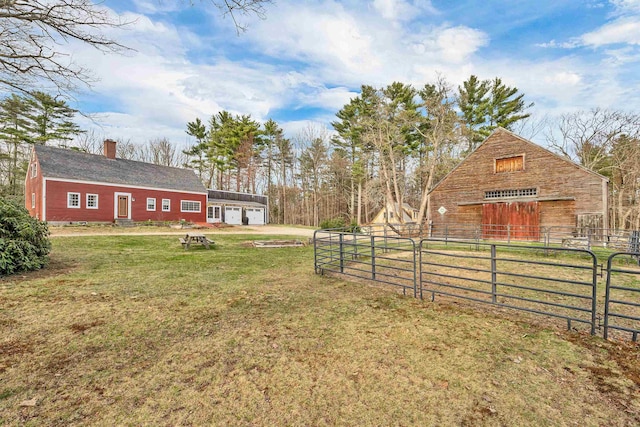 view of yard featuring fence, a detached garage, and an outbuilding